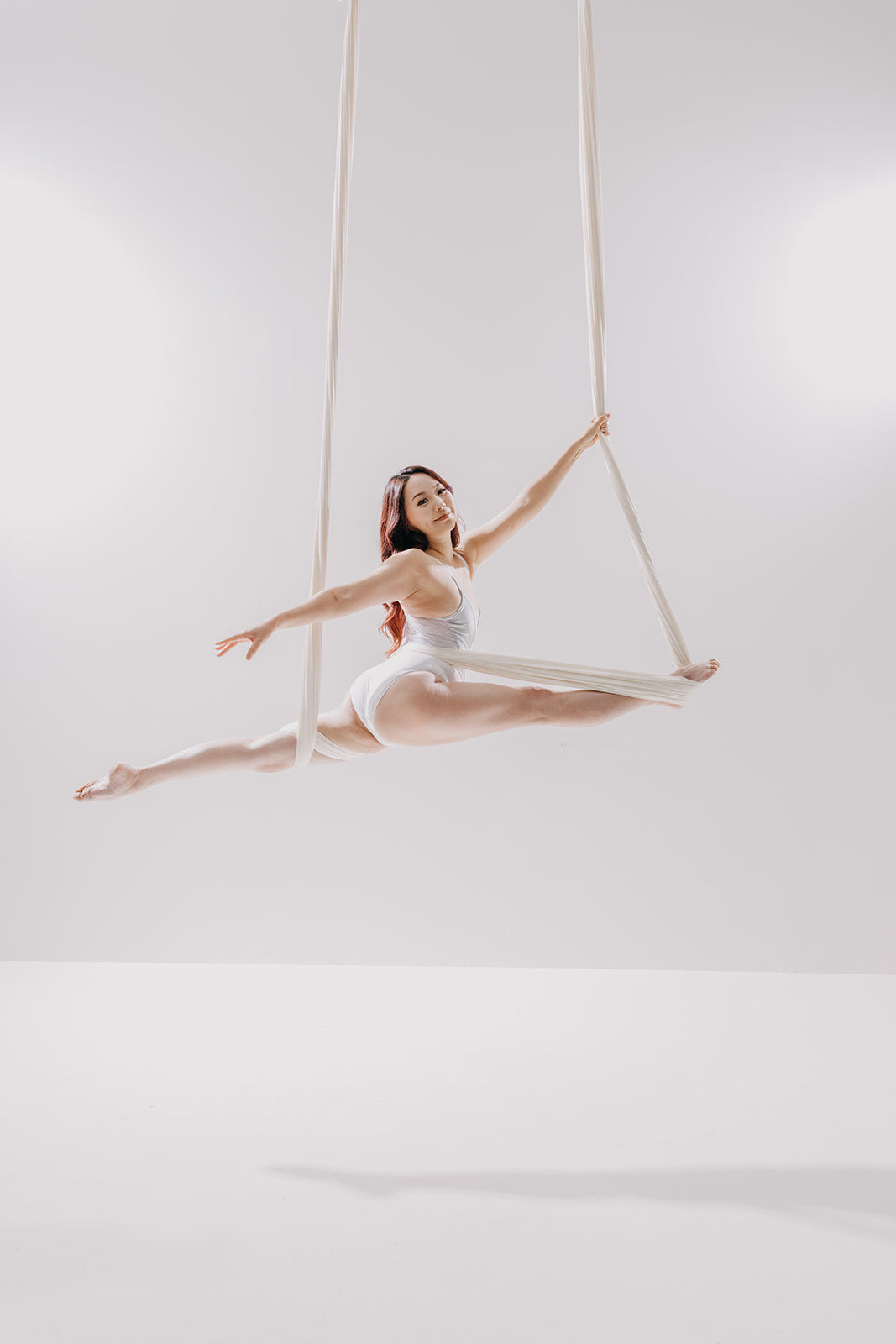 Dancer in a white aerial hammock on the light set