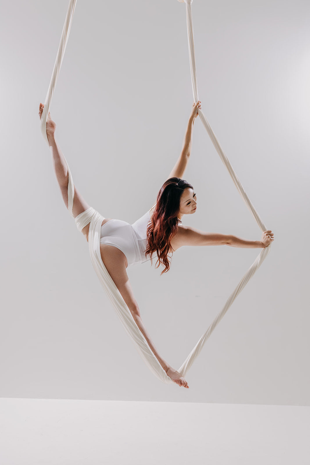 Dancer in a white aerial hammock on the light set