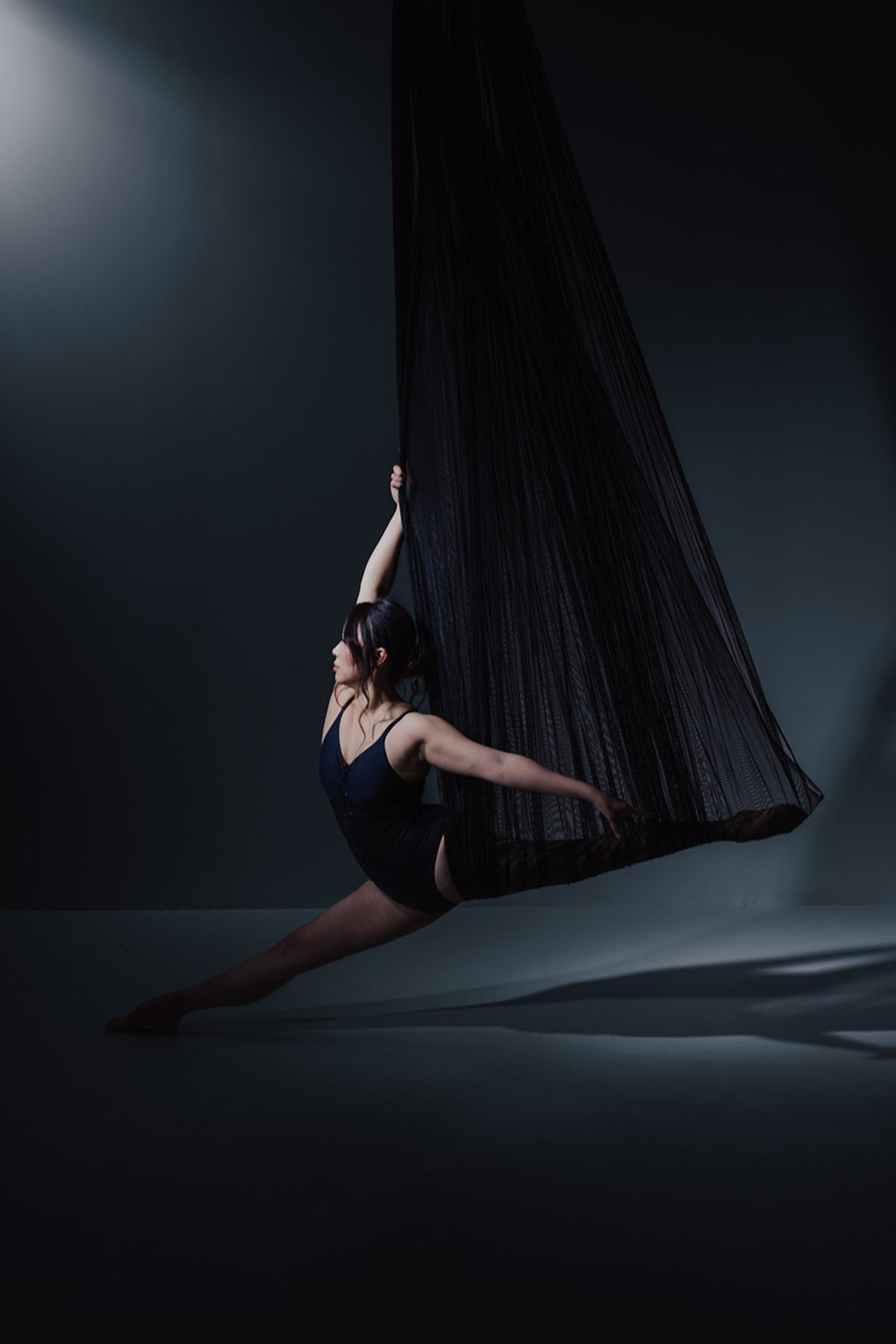 Dancer in black aerial fabric on the dark set