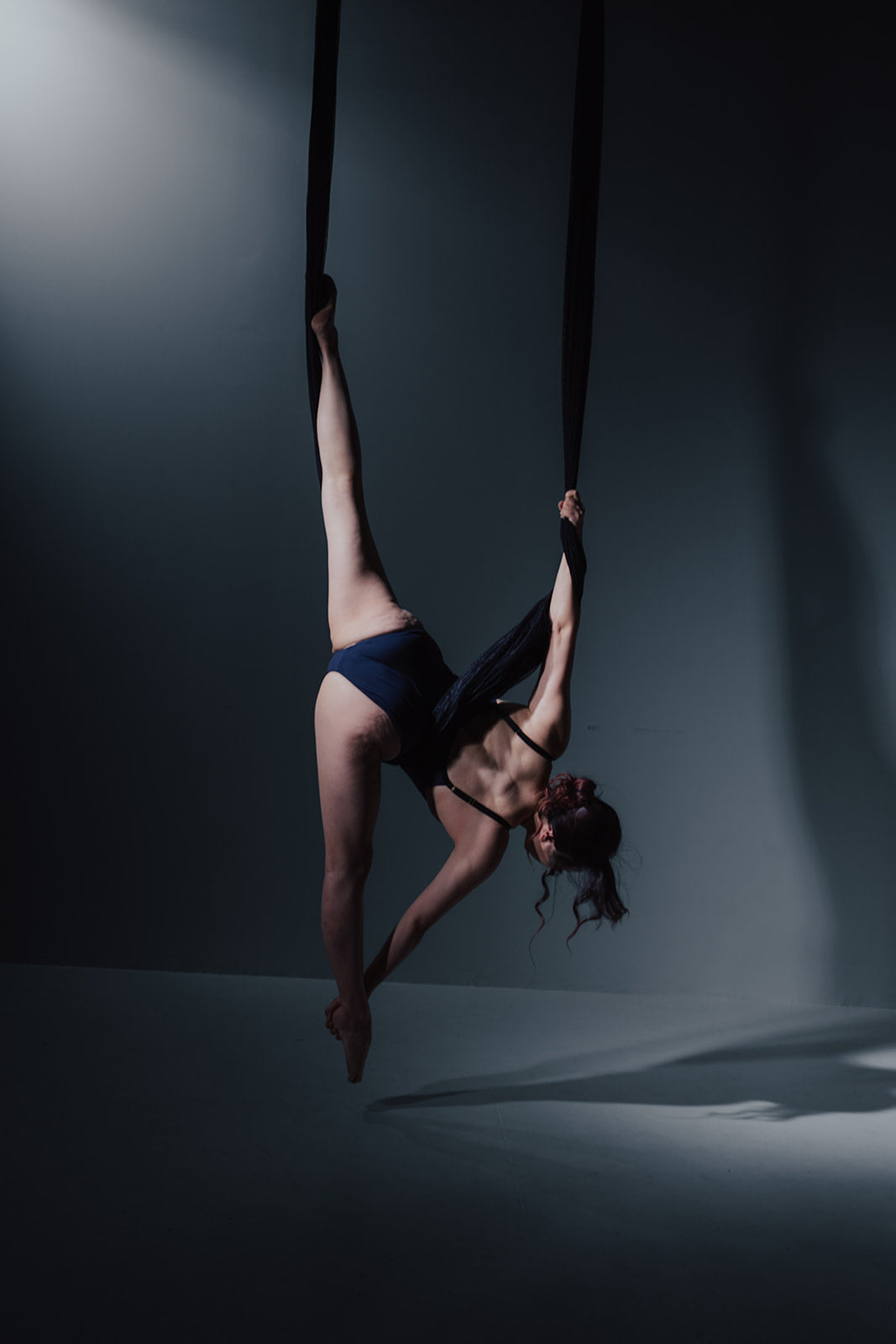 Dancer in black aerial fabric on the dark set
