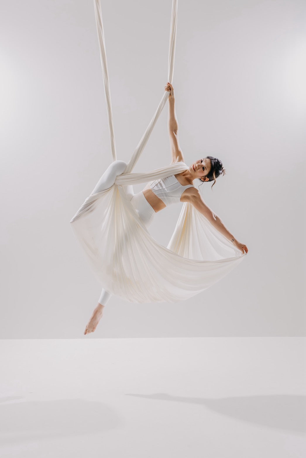 Dancer in a white aerial hammock on the light set