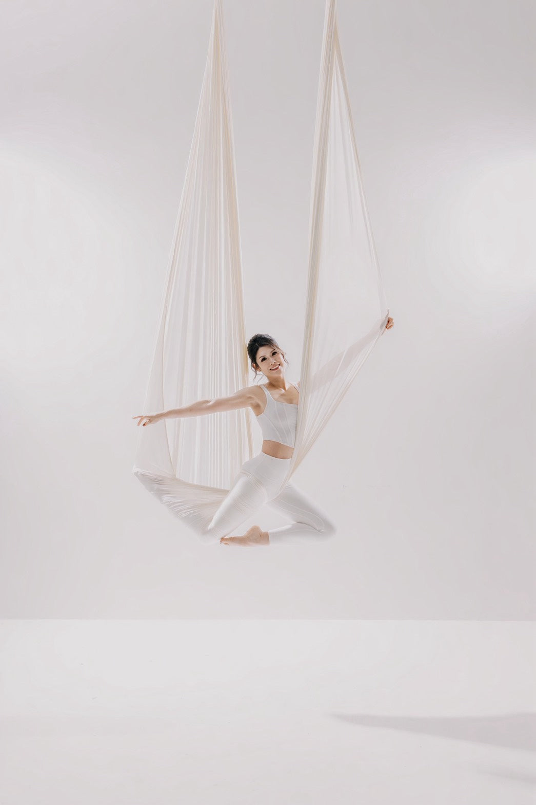Dancer in a white aerial hammock on the light set