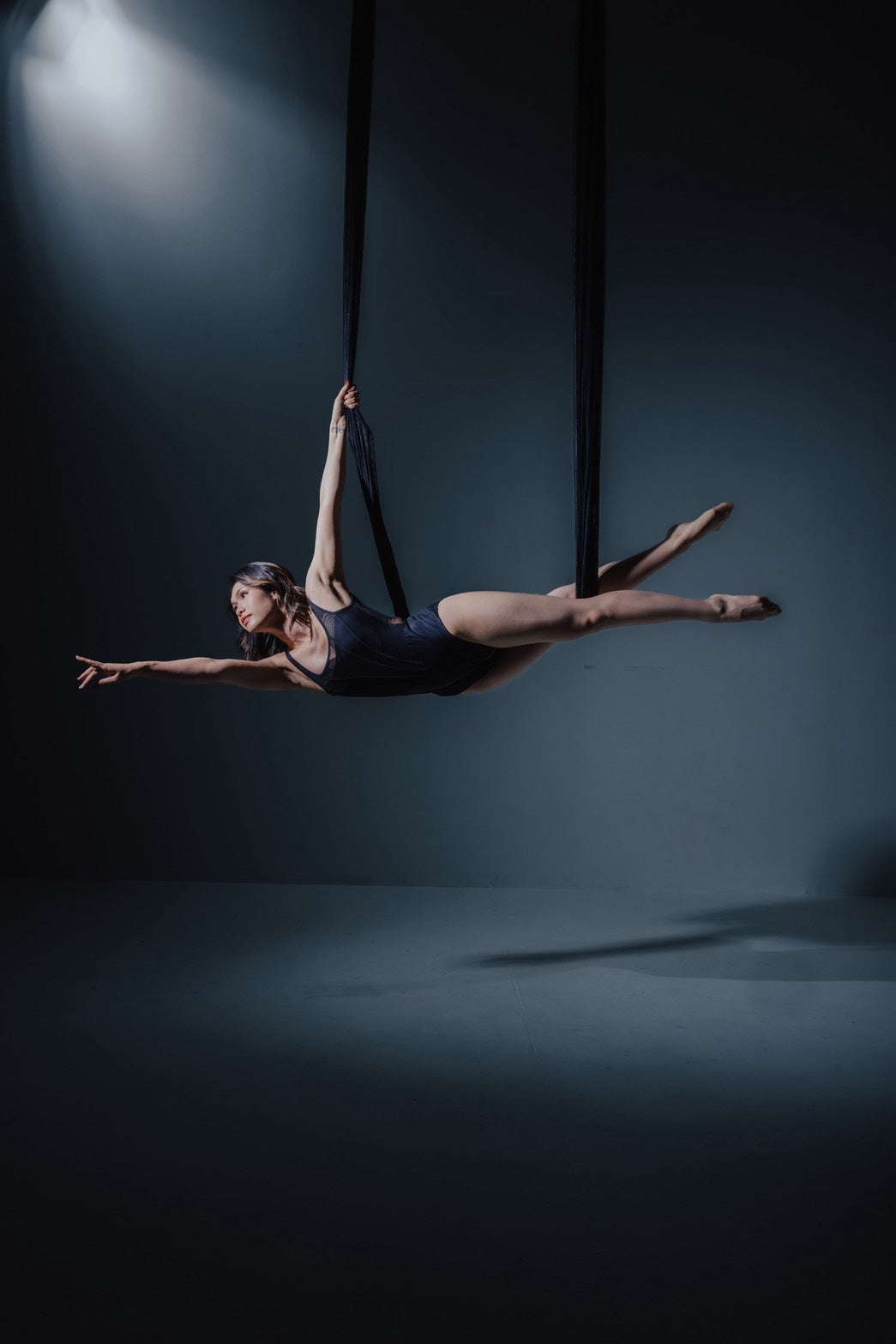 Dancer in black aerial fabric on the dark set