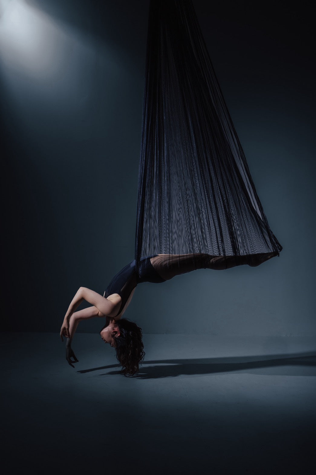 Dancer in black aerial fabric on the dark set