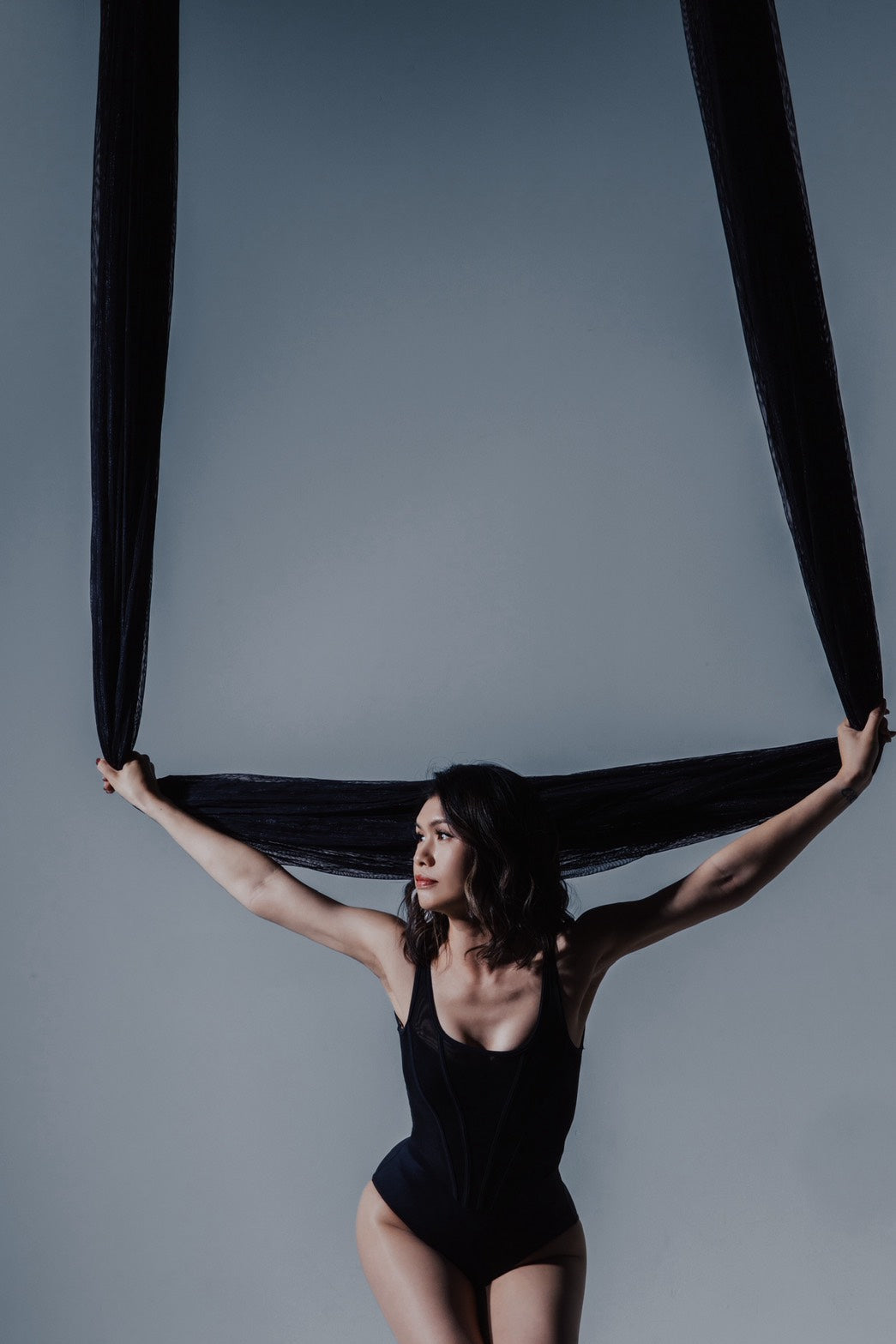 Dancer in black aerial fabric on the dark set