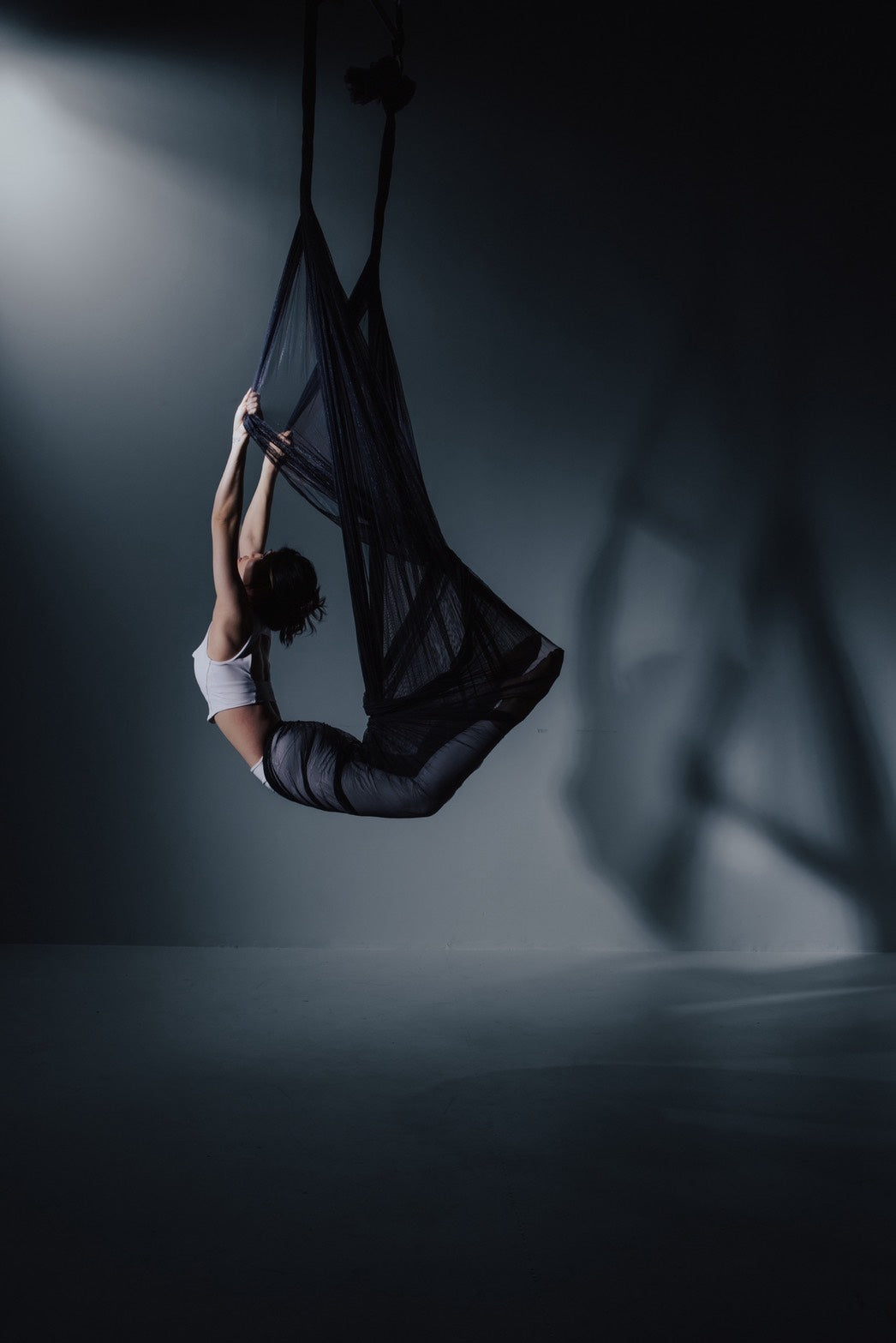 Dancer in black aerial fabric on the dark set