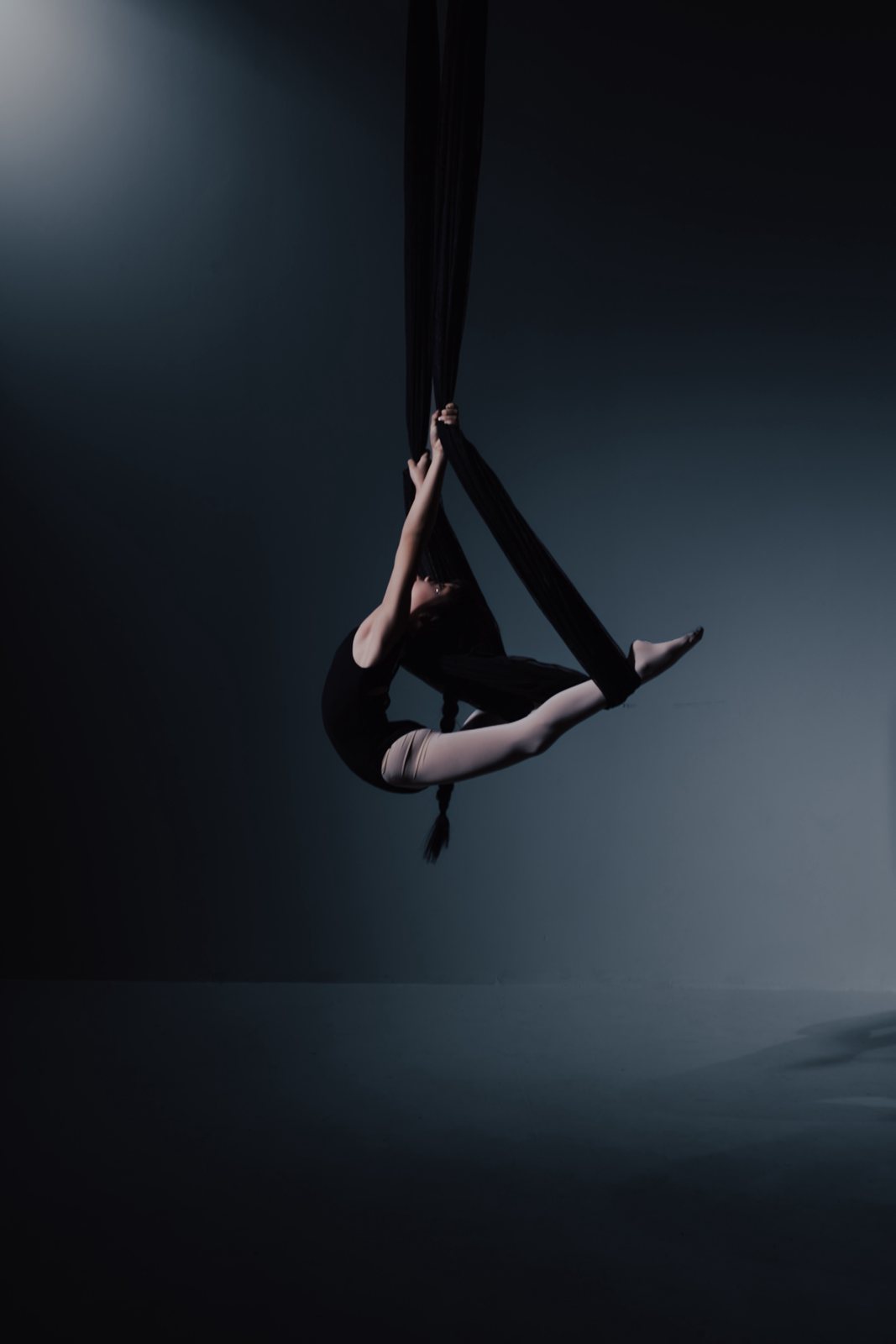 Young dancer in a black aerial hammock on the dark set