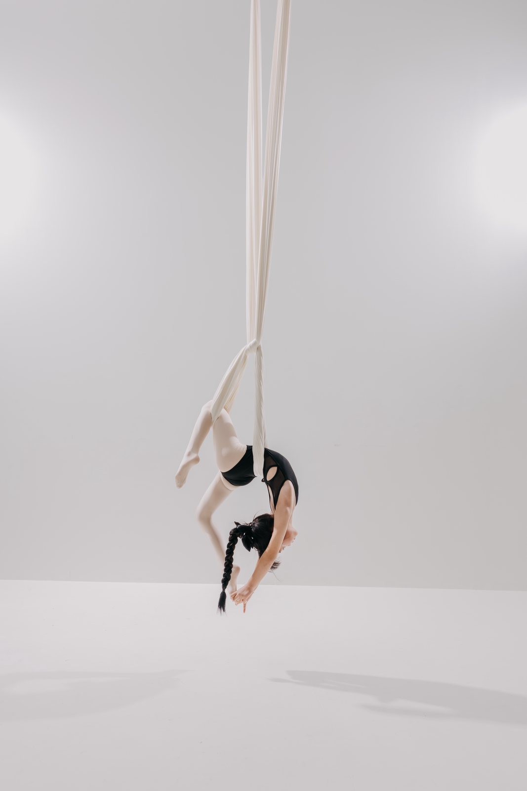 Young dancer inverted in a white aerial hammock