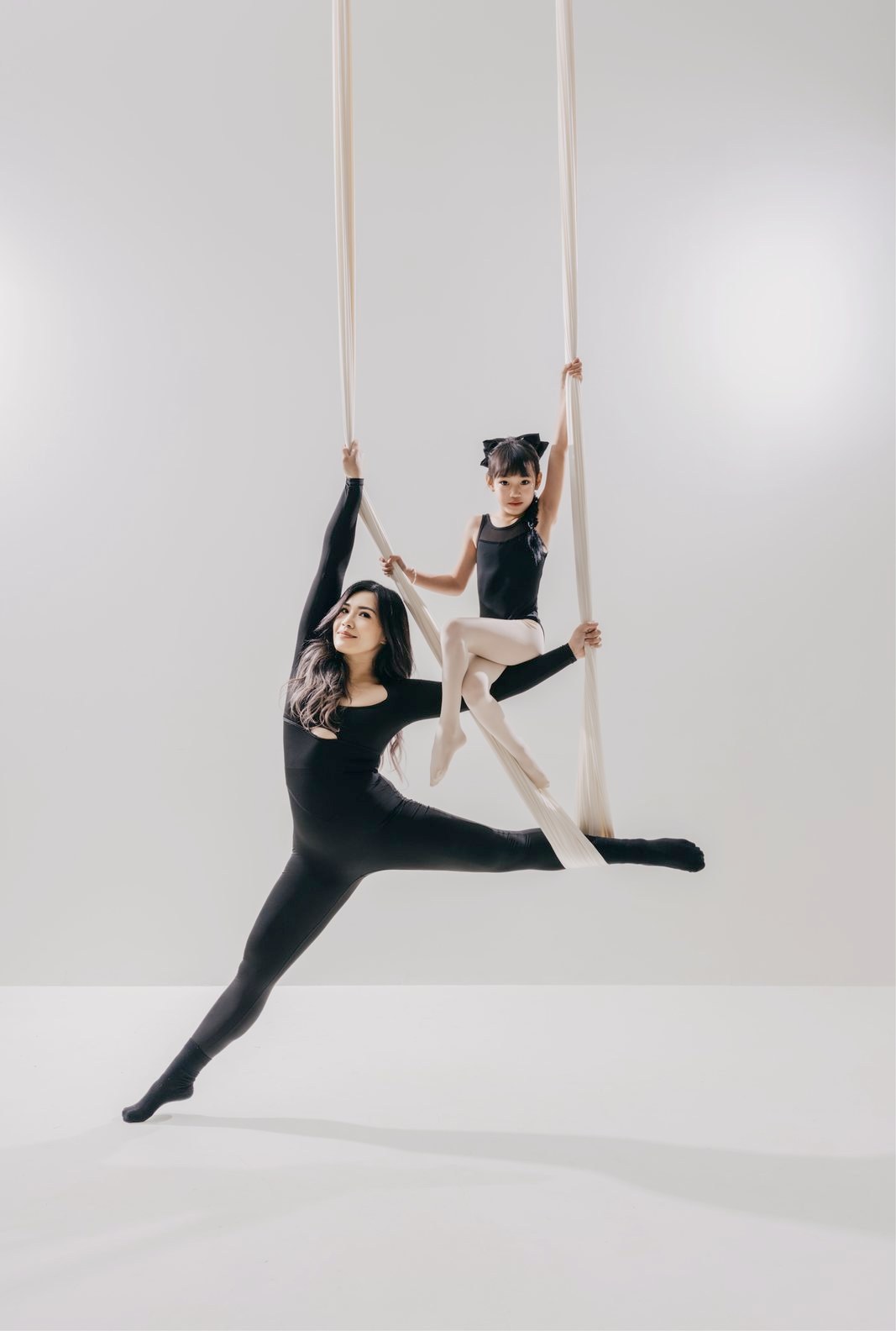 Mother and daughter together in a white aerial hammock